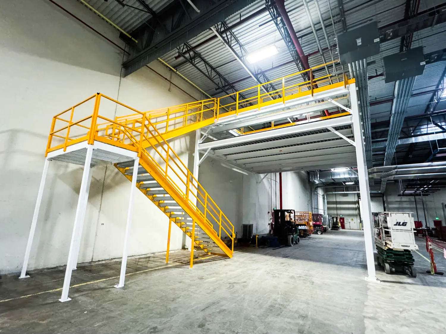 Double-deck structural steel mezzanine with yellow safety railings in warehouse